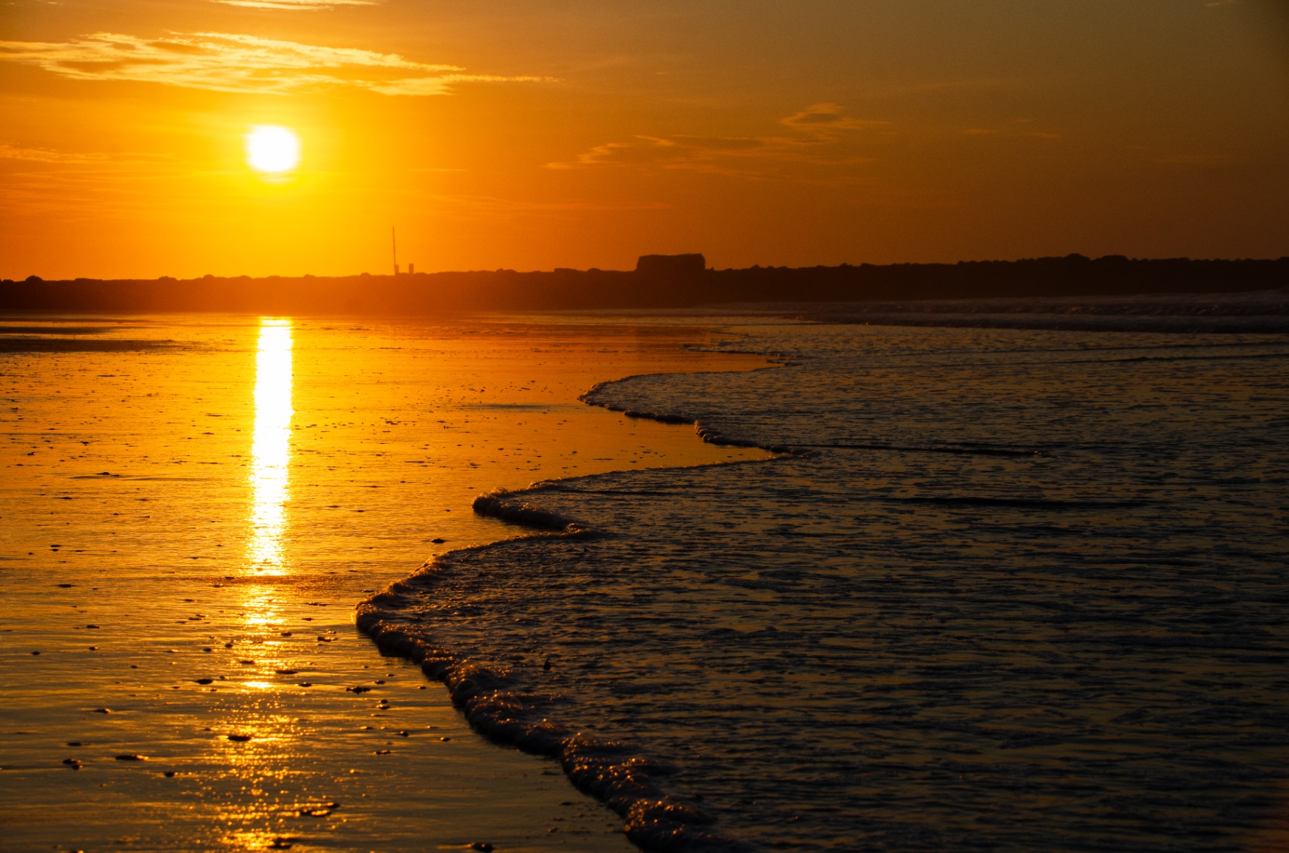 Golden sunset over the ocean with waves rolling onto the shore